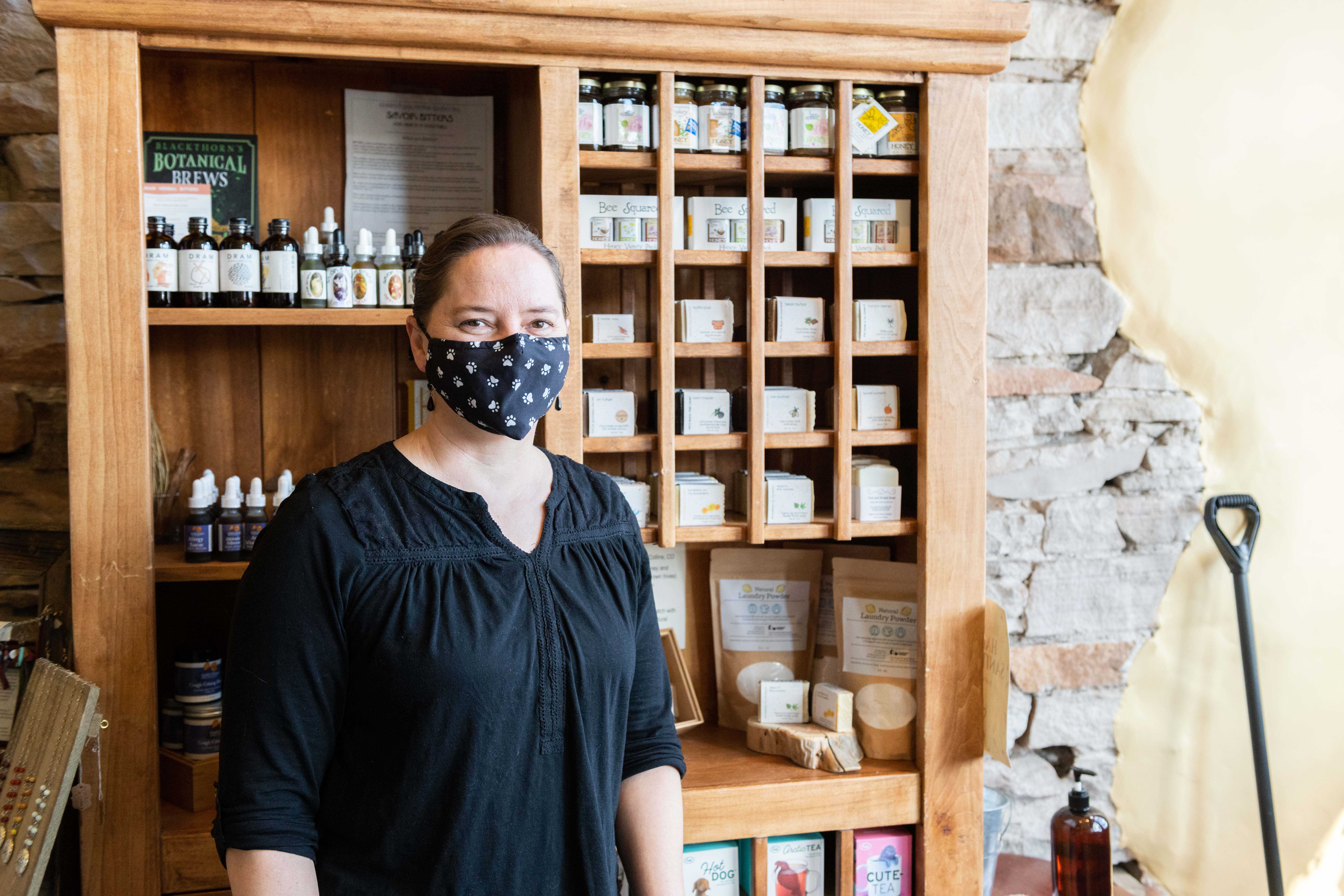Marisa May, Sunlit Mountain founder, stands next to a shelf of her products