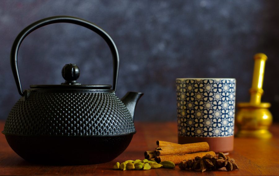 black teapot next to cup of chai