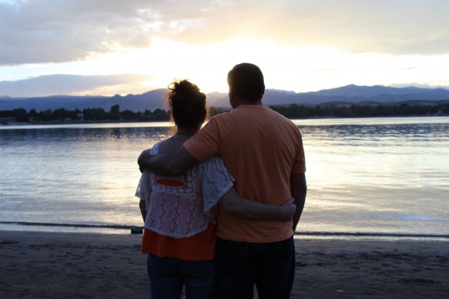 two people with arms around each other watching the sunset