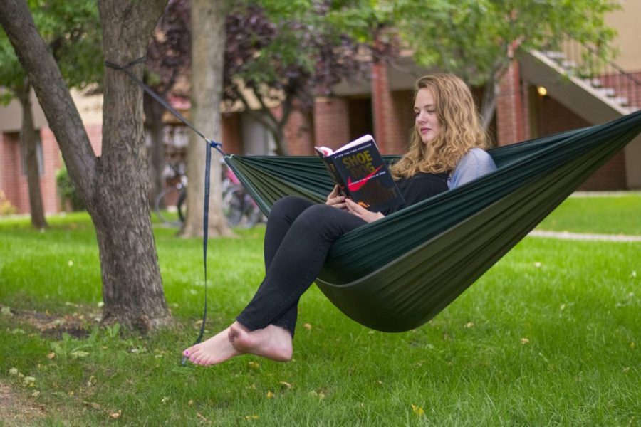 A girl sits in a green hammock reading the book Shoe Dog.