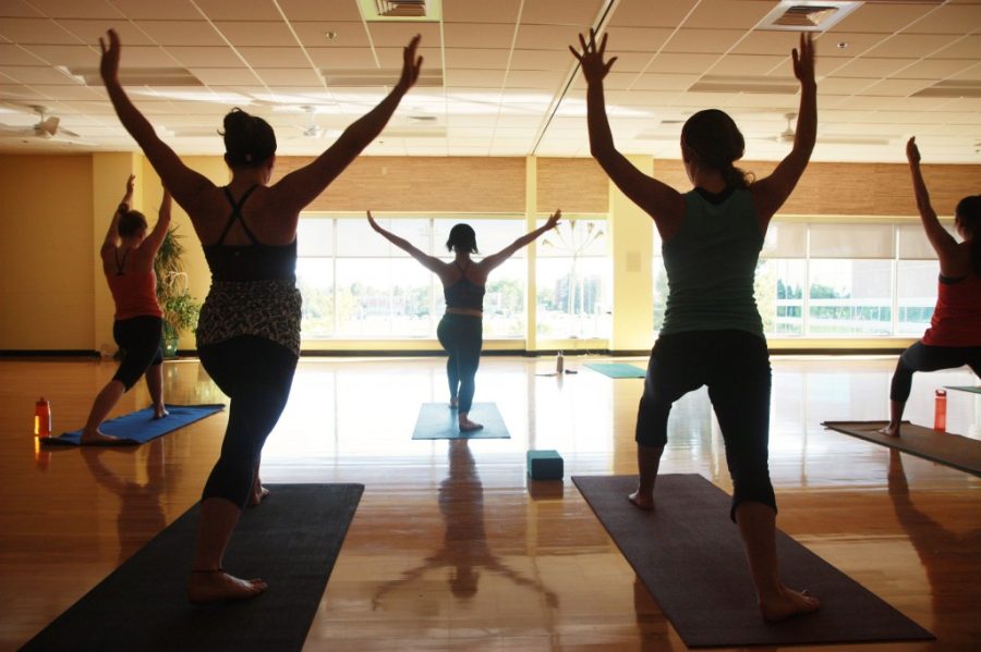 people in arms raised yoga pose silhouetted by window light