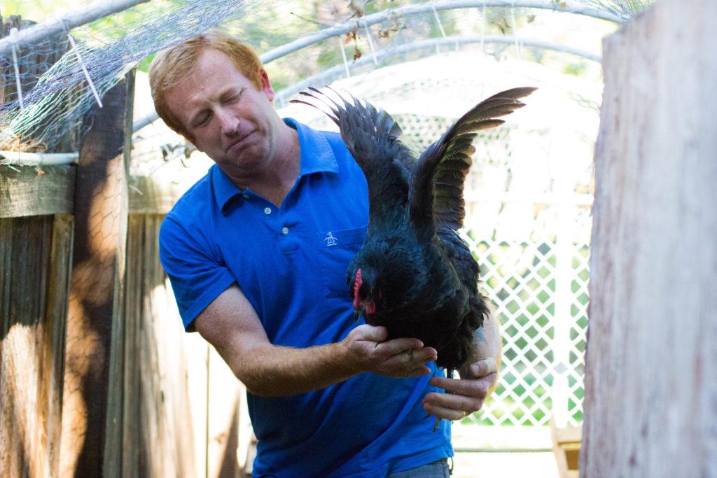 man holding a chicken while it flaps it wings