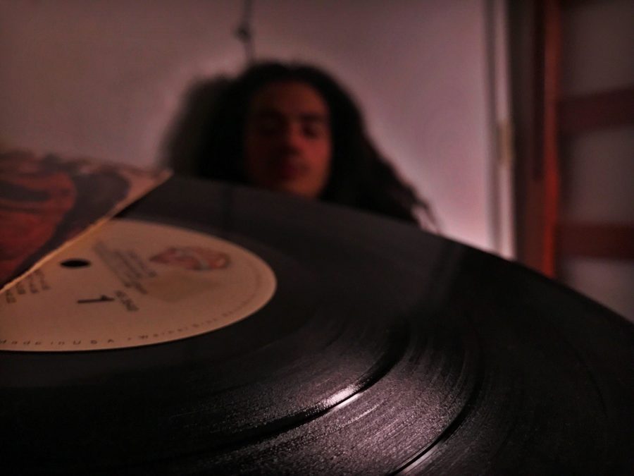 close up of a vinyl record with a person out of focus behind it