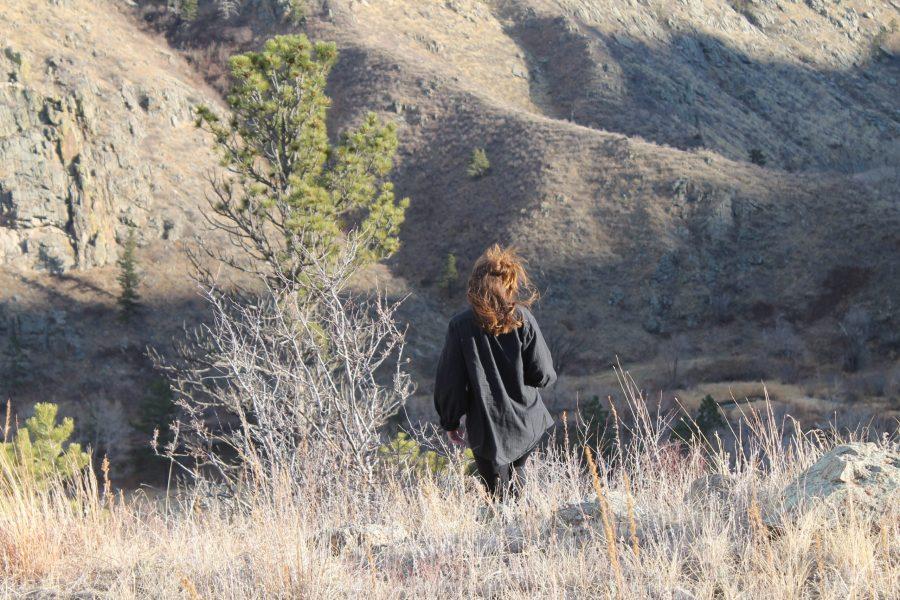 person+with+long+brown+curly+hair+standing+in+front+of+foothills