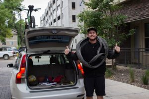 Jimmy Yoder posing by his car with his mountain bike tires on his neck.