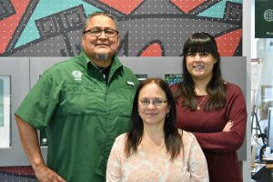 Director of NACC Ty Smith (left), Assistant Director Tiffani Kelly (right), and Administrative Assistant Teresa Rice (center) stand in front of the cultural center in the LSC. Photo credit: Kelly Peterson