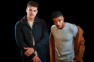 two men, one white, one black, posing fashionably in nice jackets