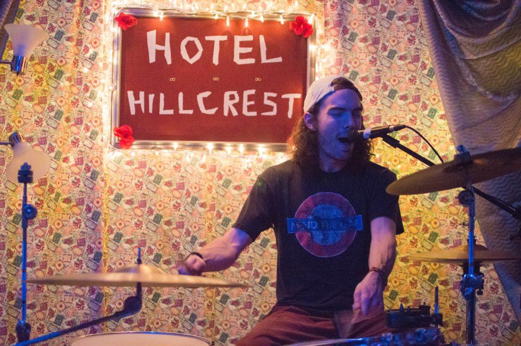 DIY venues in Fort Collins: Drummer playing music in front of Hotel Hillcrest sign