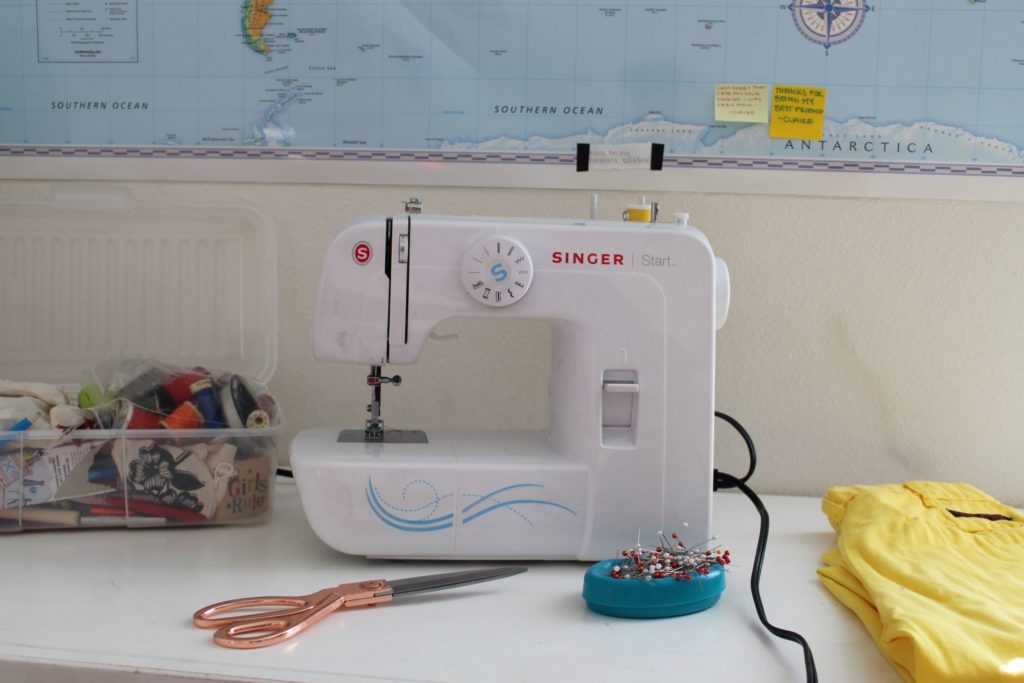 A white sewing machine on a desk workspace meant for clothing alterations