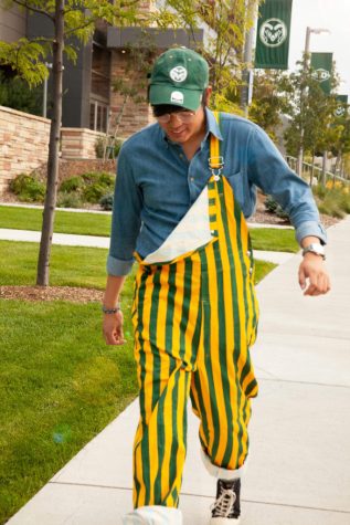 man poses in green and yellow striped overalls
