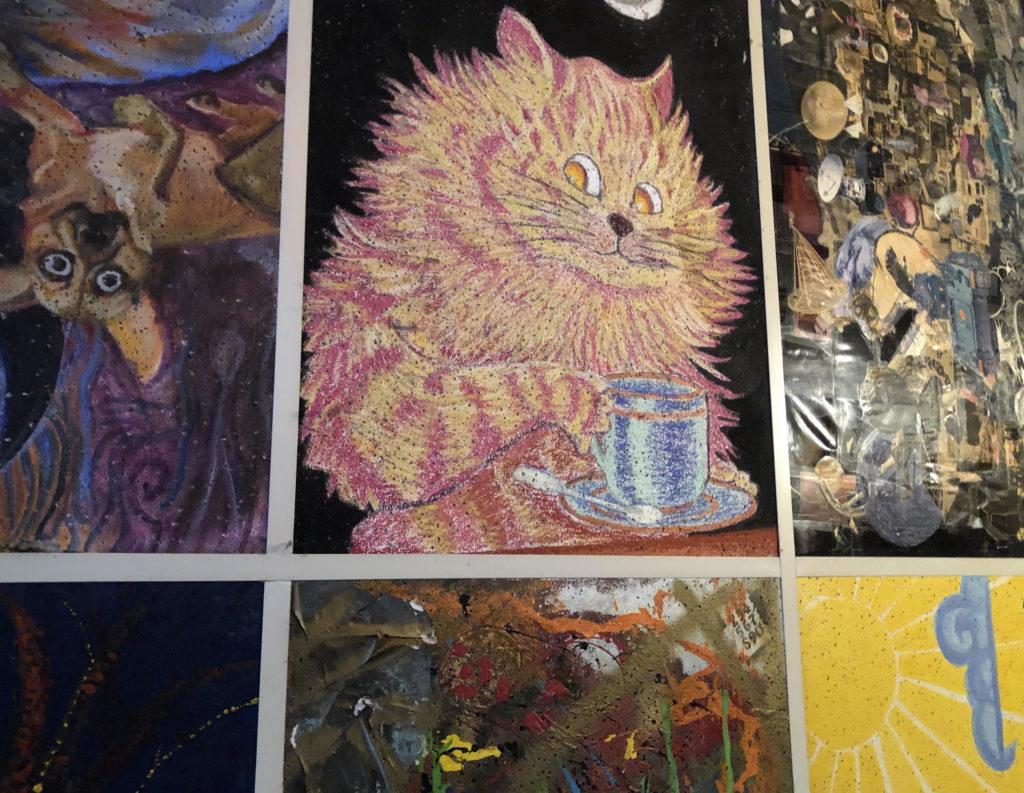 Artwork of pink and yellow cat drinking coffee