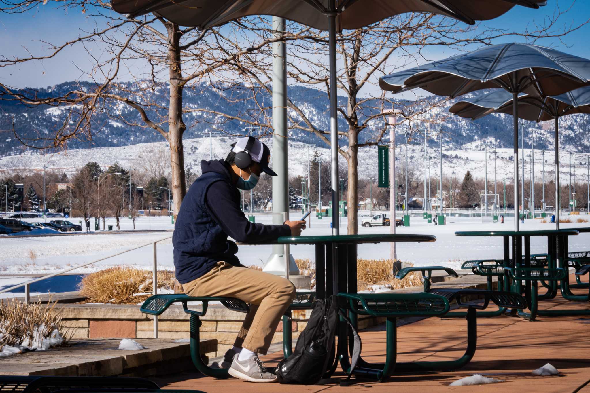 Man sitting at table outside CSU wearing a mask