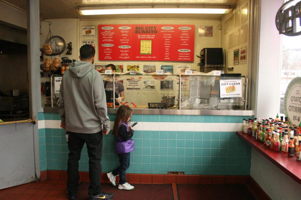 adult man and little girl order from the counter of Big City Burrito