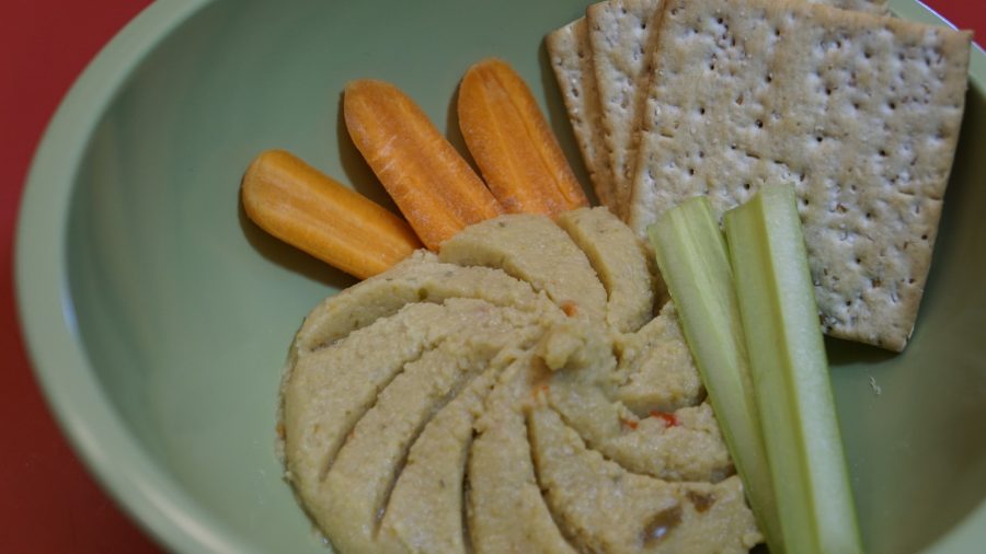 close up of hummus platter with carrots and crackers and celery