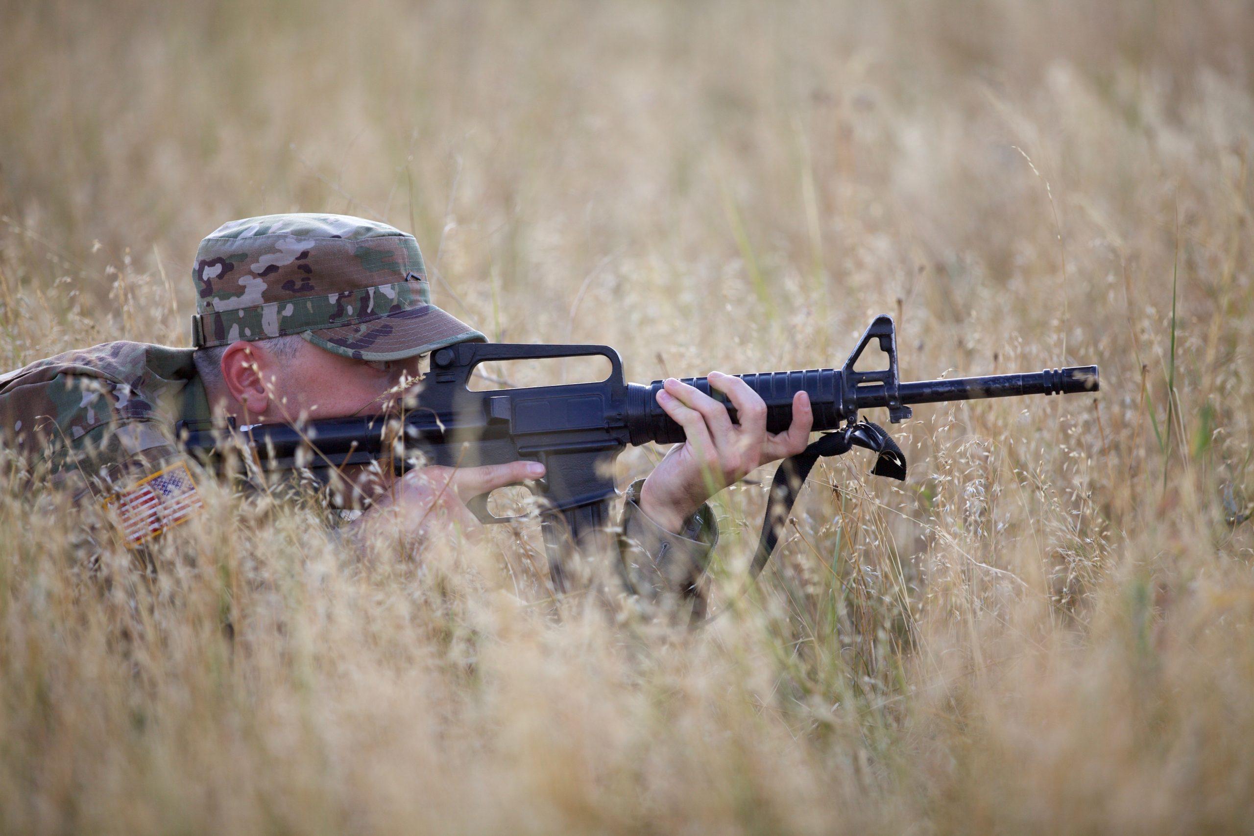 man aiming gun in field