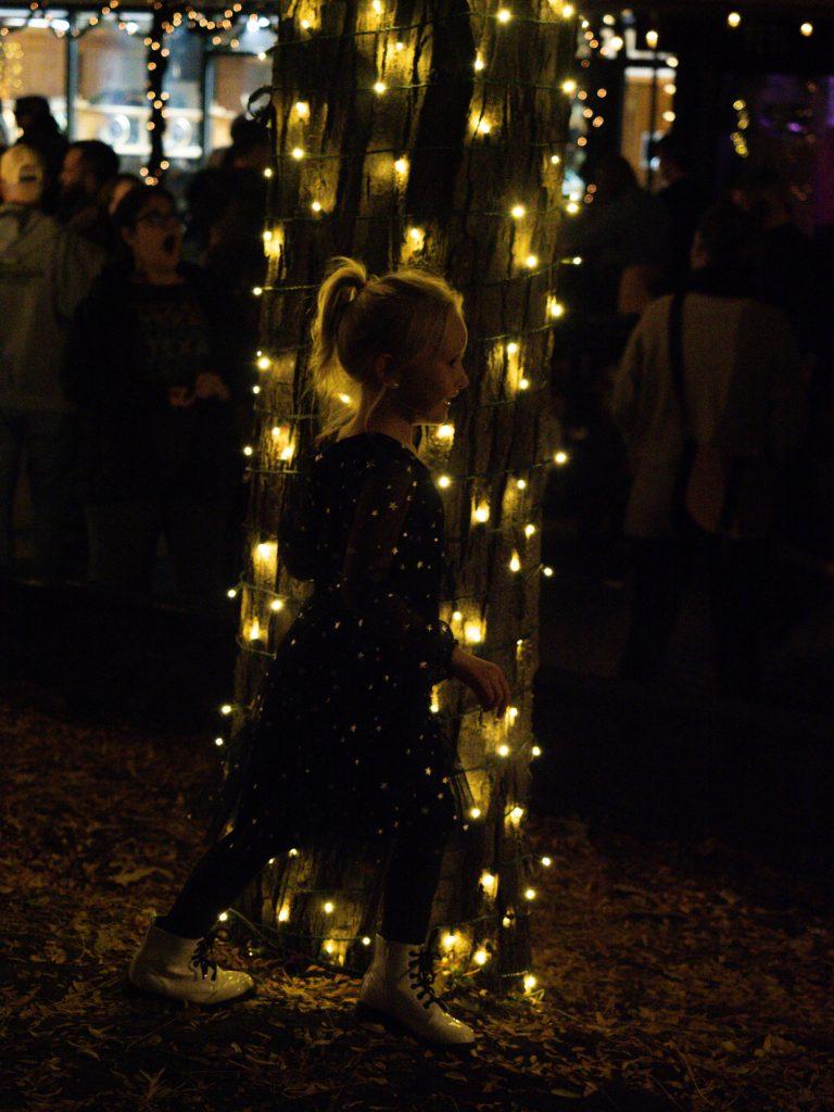 Girl stands in front of tree lights