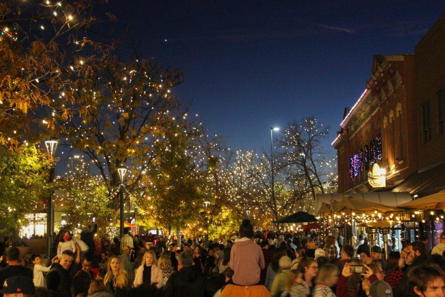 A young girl sits on her father’s shoulders as they walk the lit streets of Old Town Fort Collins, Nov 5. The streets were crowded with people enjoying the open shops and the holiday lights.  (Sophia Stern | The Collegian