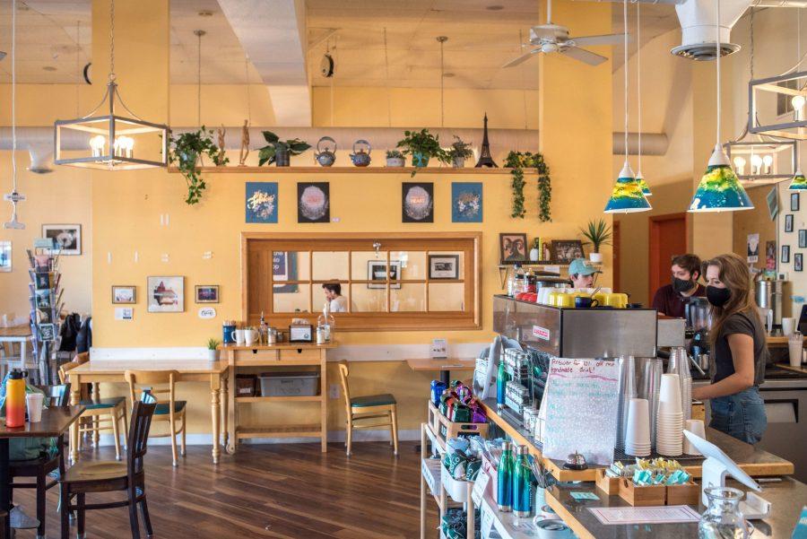 The order counter at the Momo Lolo Coffee Shop, next to a wall with plants and art, lit with sunlight Dec 7. (Pratyoosh Kashyap | College Avenue Magazine)