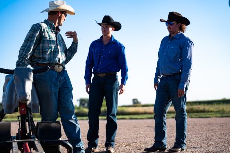 cowboys standing around a calf learning proper techniques
