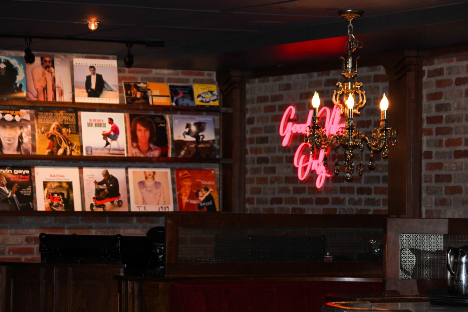 A wall of records decorates the Ace Gilletts bar along with a neon sign and chandeliers over the booths.