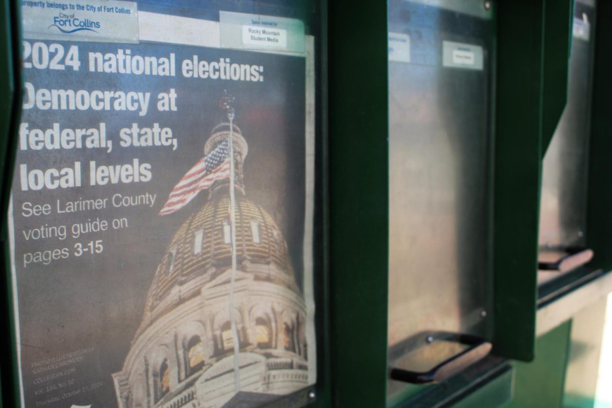 The front page of the Rocky Mountain Collegian is displayed in a newsrack.