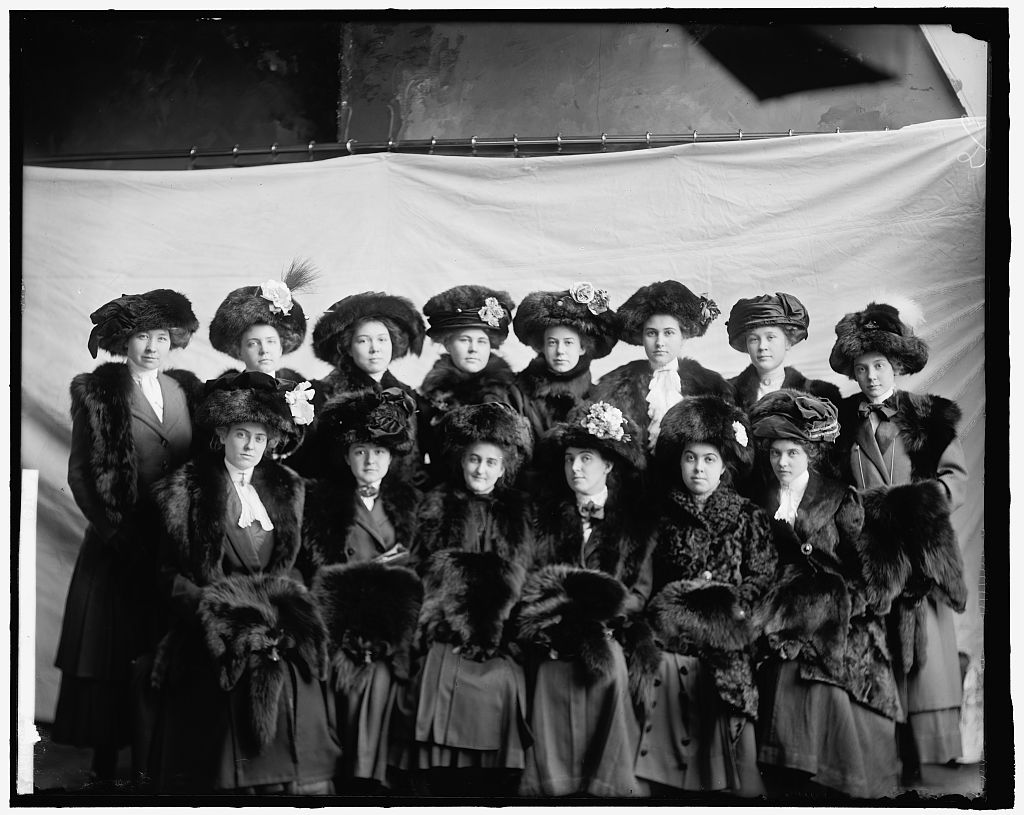 A group of women wearing matching black outfits pose for a portrait.