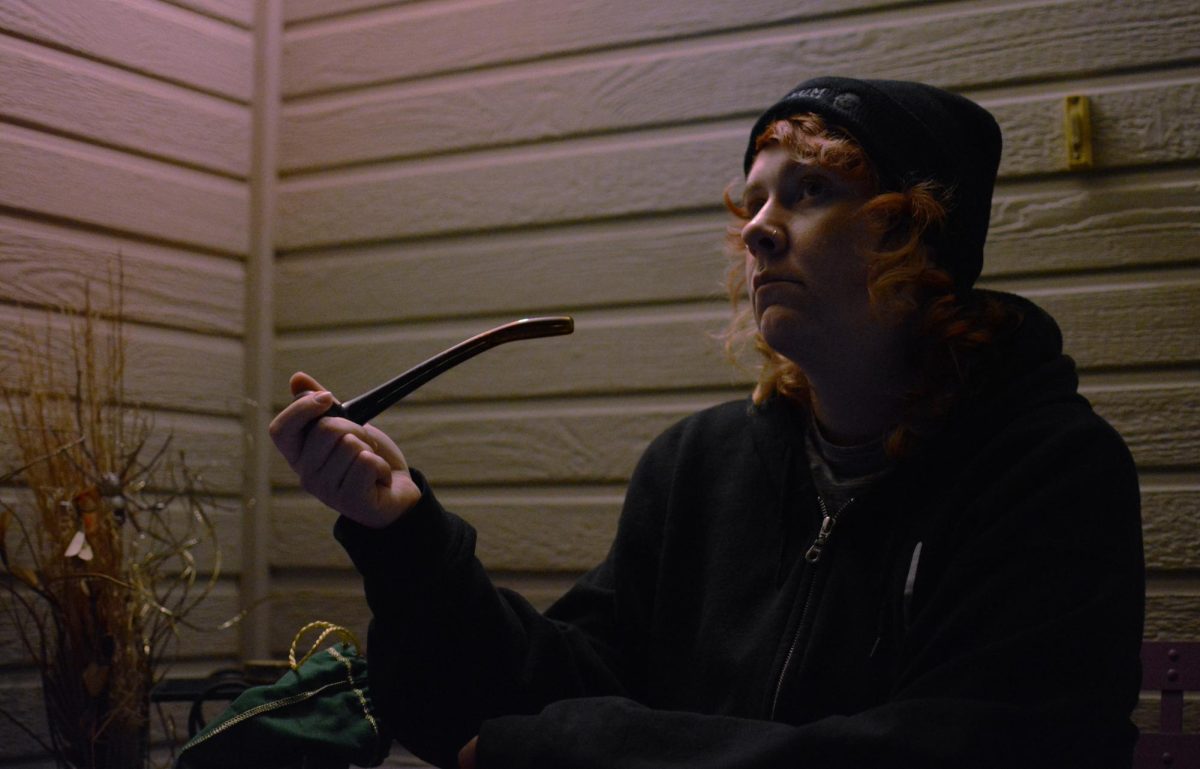 Ashley Baron sits outside of her home, holding a pipe and staring out into the parking lot in Fort Collins March 20. She often uses electric pens, but once in a while she will use a traditional pipe.